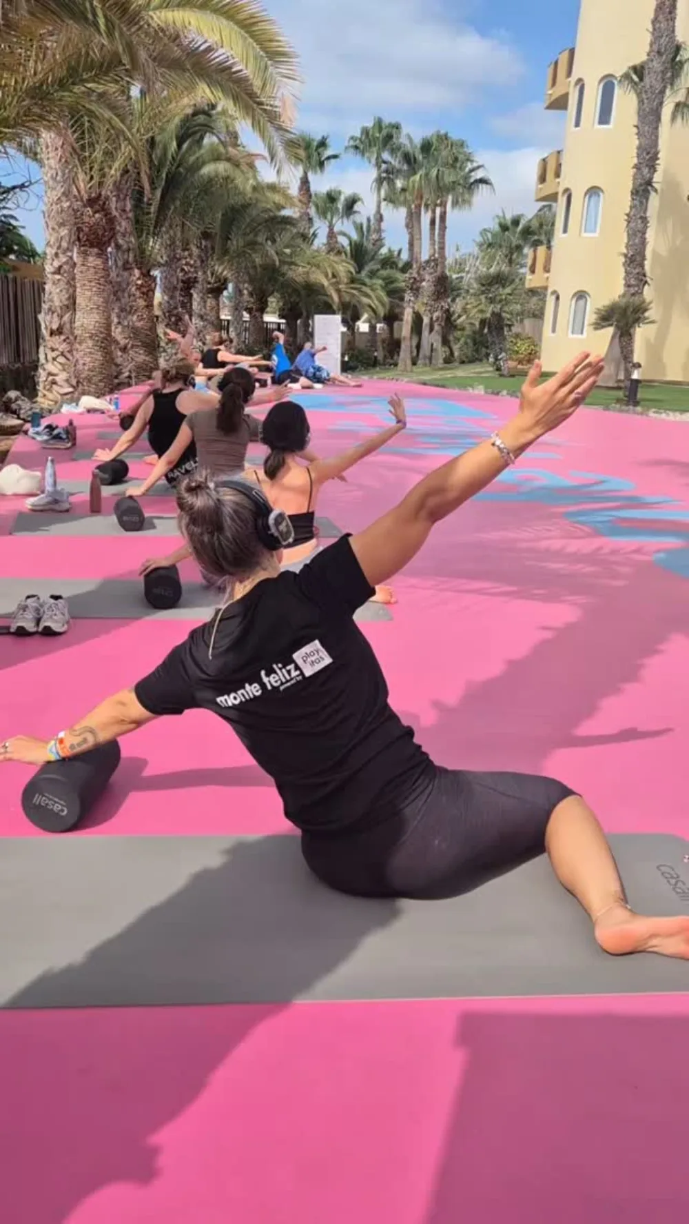 Emma leder ett foam roller-pass utomhus på en rosa plan