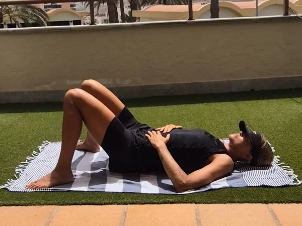 Emma ligger på rygg på en matta med böjda knän och tennisbollar under sacrum